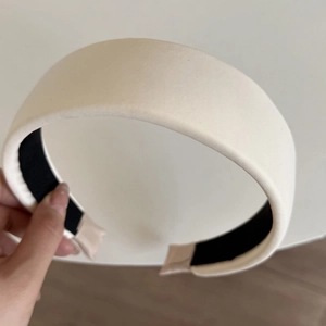 Detail of a thick padded cream satin headband featuring a black non-slip inner lining