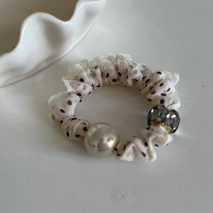 Détail de chouchou en dentelle à pois avec perle nacrée et cristaux gris brillants