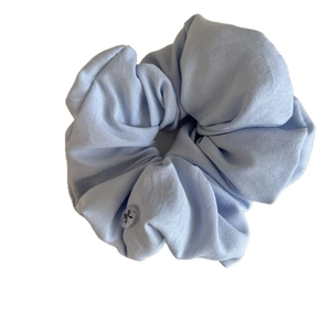 Light blue fabric scrunchie with button detail and bow print on a white background