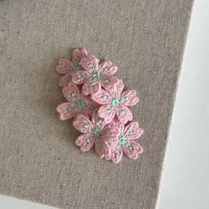 Barrettes à cheveux fleurs de cerisier tricotées roses avec perle sur fond de lin gris