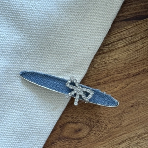 Barrette en jean bleu avec nœud en strass et bords effilochés vintage sur tissu blanc