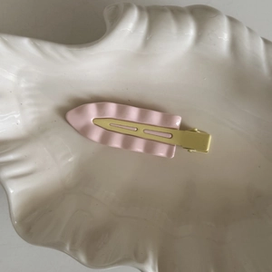 Fermaglio per capelli in metallo rosa ondulato a contrasto su vassoio in ceramica bianca
