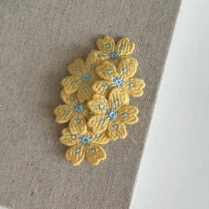 Détail de barrettes fleurs brodées jaunes avec perles bleues pour coiffure de fille