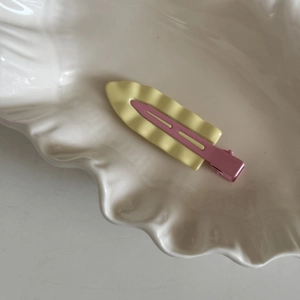 Dettaglio del fermaglio a onde in giallo pastello e rosa cipria su ceramica