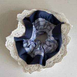 Detail of navy striped fabric scrunchie with elegant cream floral lace trim edges