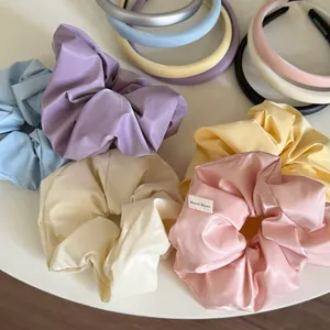 Nahaufnahme bunter Satin-Haargummis und Stirnbänder mit handgefertigtem Label-Detail