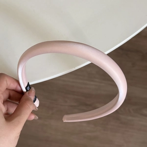 Detailaufnahme eines rosa Satin-Haarreifs mit glatter Stoffstruktur und edlem Design