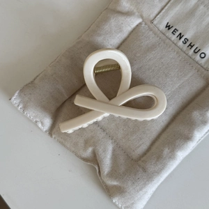Nahaufnahme der minimalistischen cremeweißen Acryl-Haarklammer mit goldener Metallfeder