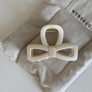 Detail einer cremeweißen Haarklammer mit Schleife und goldener Metallfeder für Damen