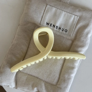 Nahaufnahme der cremefarbenen Acryl-Haarklammer mit gedrehtem Design auf weichem Stoff