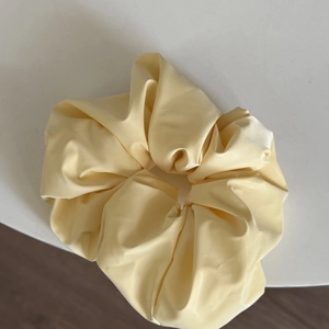 Nahaufnahme von hellgelbem Satin-Scrunchie mit glänzender Textur und edlen Stofffalten