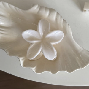Pince à cheveux fleur de frangipanier blanche élégante avec fini perlé sur plateau
