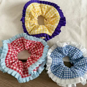 Gros plan sur trois chouchous à carreaux avec bordures volantées en jaune, rouge et bleu