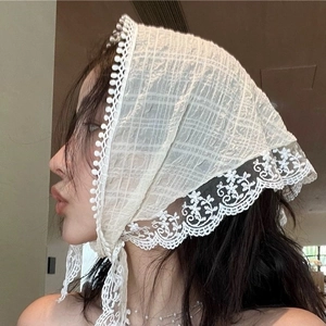 Gros plan du foulard triangulaire en dentelle blanche avec broderie florale et détails pompons