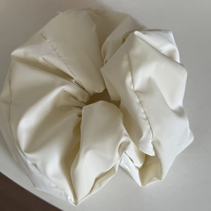 Nahaufnahme von cremeweißem Satin-Haargummi mit glänzender Textur und Falten-Design