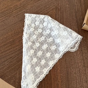 Gros plan du foulard triangle en dentelle blanc crème avec broderie sur bois