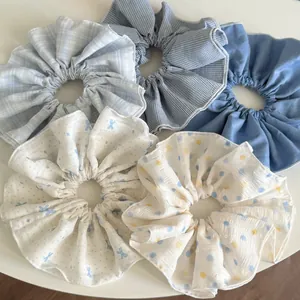 Flat lay of five assorted blue polka dot and plaid pattern fabric scrunchies for hair