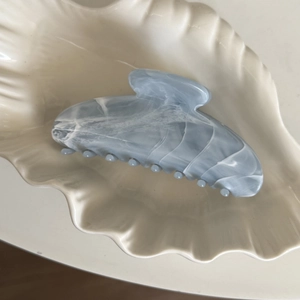 Gros plan sur la texture marbrée bleue et blanche de la grande pince à cheveux à griffes