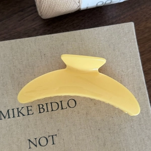 Dettaglio macro della clip per capelli gialla lucida su libro con luce calda ed estetica