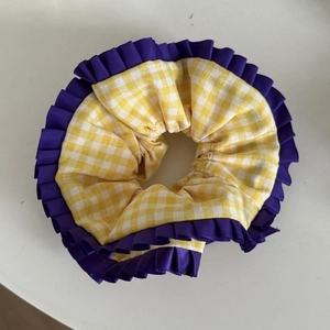 Vue détaillée du chouchou à carreaux jaune et blanc avec bordure en ruban violet
