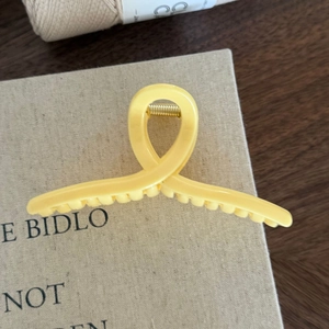 Dettaglio della molletta per capelli geometrica giallo crema con molla dorata