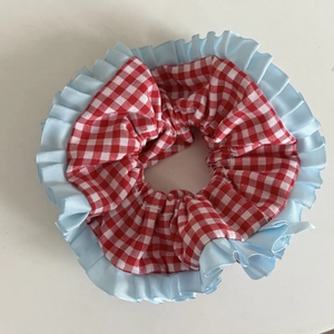 Détail d'un chouchou à carreaux rouges et blancs avec bordure en dentelle plissée bleue