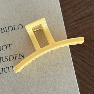 Macro di una molletta per capelli rettangolare giallo opaco con dettagli in metallo oro