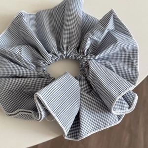 Close-up detail of blue and white gingham fabric scrunchie with fine stitching