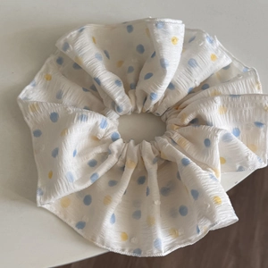 Macro detail of large white scrunchie with colorful dots on a textured fabric