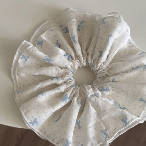 Detailed view of white scrunchie with light blue bow and polka dot patterns