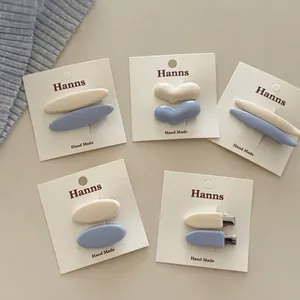 Set di fermagli per capelli a cuore crema e blu opachi su cartoncino bianco