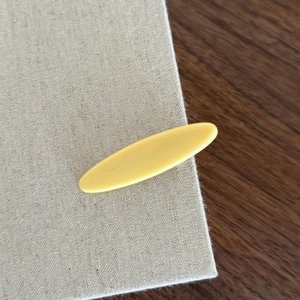Dettaglio di un fermaglio per capelli giallo opaco ovale su superficie testurizzata