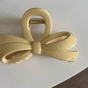 Minimalist cream yellow bow hair claw clip with glossy finish and gold metal spring