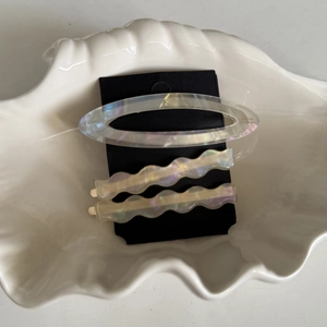 Detailed view of iridescent acetate hair clip set with wavy pins on shell display