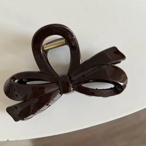 Glossy chocolate brown bow-shaped hair claw clip with golden metal spring and fine teeth
