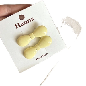 Paire de barrettes à cheveux en forme de nœud jaune crème sur carte de marque
