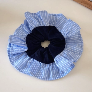 Detail of blue striped and navy dual-layer fabric scrunchie with soft ruffled edges