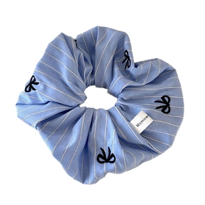 Blue and white striped scrunchie with black bow embroidery and brand tag on white background