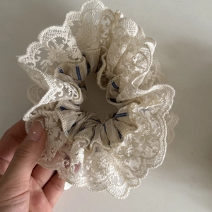Détail de chouchou en dentelle crème avec rayures bleues et bordure florale brodée