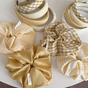 Close-up of yellow plaid and satin hair accessories with handmade labels on white background