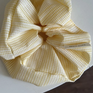 Detail of yellow plaid scrunchie with lace edges and a white hand made fabric label