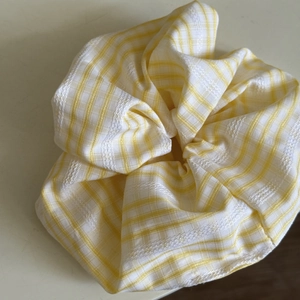 Detail showing yellow and white plaid fabric hair scrunchie with intricate embroidery