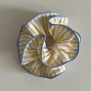 Striped yellow and white scrunchie with blue trim edges shown in a top-down view
