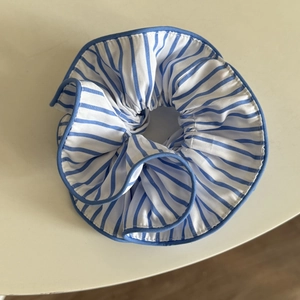 Close-up of blue and white striped fabric scrunchie with elastic pleated design