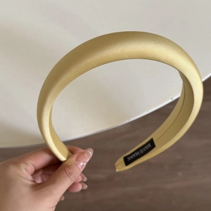 Detailed close-up of handmade yellow satin padded headband with premium brand label