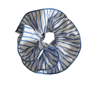 Chic blue and white striped fabric scrunchie with blue edge trim on white background
