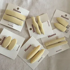 Detailed view of handmade cream yellow fabric hair clips on a branded display card