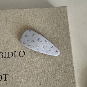 Vue détaillée de la texture du tissu floral sur la pince à cheveux triangle bleu clair