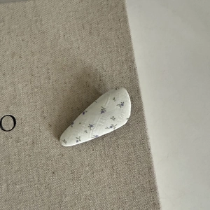 Gros plan d'une barrette triangle en tissu avec des motifs floraux violets et doux