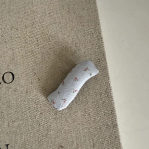 Gros plan d'une pince à cheveux en tissu floral avec de petits motifs rouges sur textile